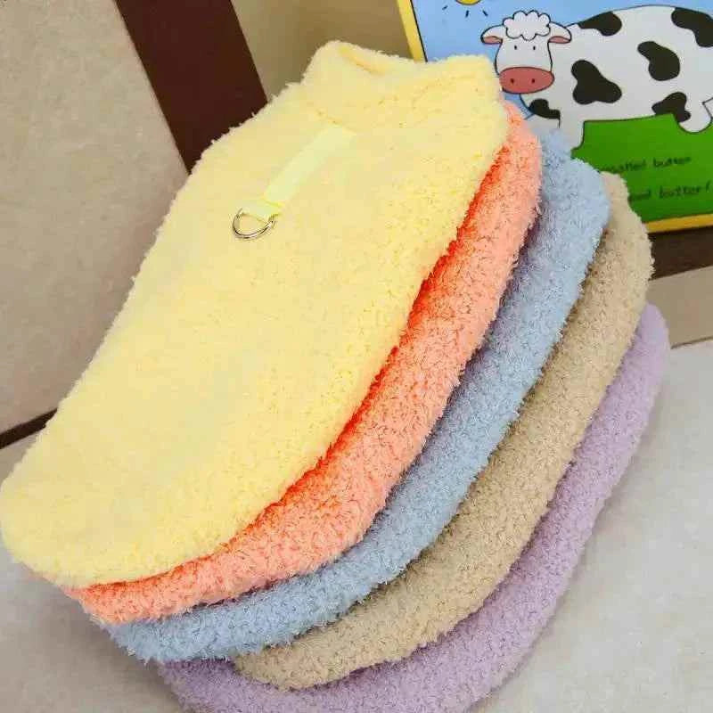 Plush winter dog coats in soft pastel colors stacked, insulated and cozy for cold weather